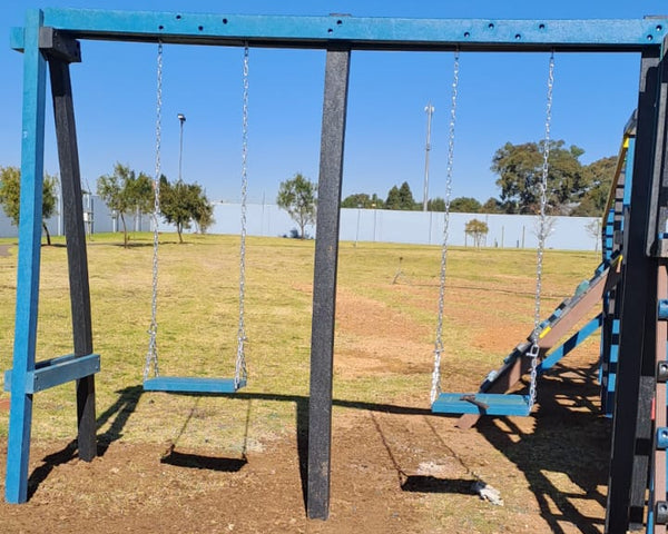 A two-seater swing set made of metal, painted in blue and green, standing on a grassy field.